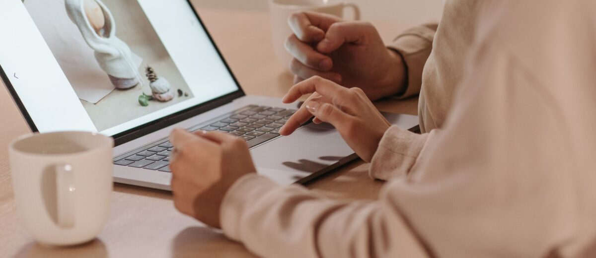 Two individuals reviewing a photo on a laptop, enjoying coffee indoors.