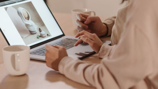 Two individuals reviewing a photo on a laptop, enjoying coffee indoors.