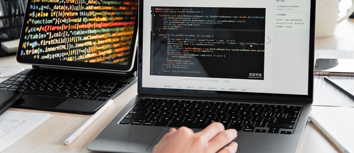 A developer writing code on a laptop, displaying programming scripts in an office environment.