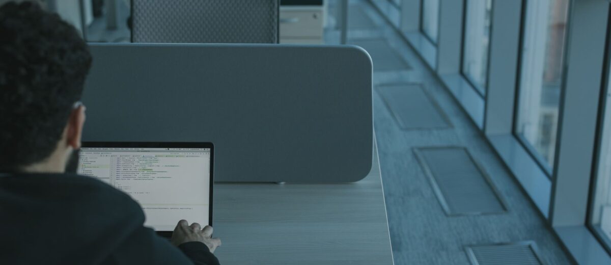 Man working on a laptop in a modern office setting, using advanced technology.