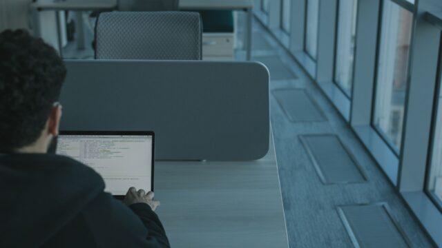 Man working on a laptop in a modern office setting, using advanced technology.