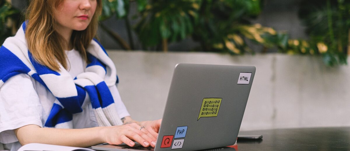 Young woman with a laptop working in a modern indoor space, showcasing freelance and digital nomad lifestyle.
