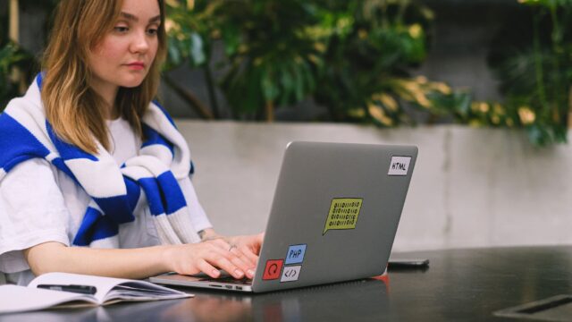 Young woman with a laptop working in a modern indoor space, showcasing freelance and digital nomad lifestyle.