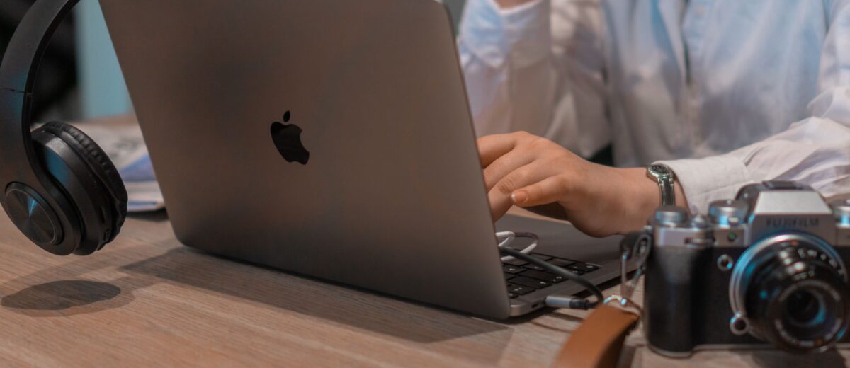 Close-up of a person working remotely with a laptop, headphones, and camera. Ideal for tech and lifestyle themes.